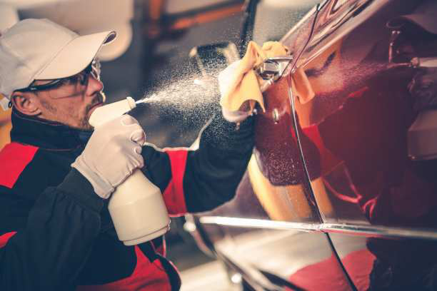 a man cleaning the car with a spray can and fabric