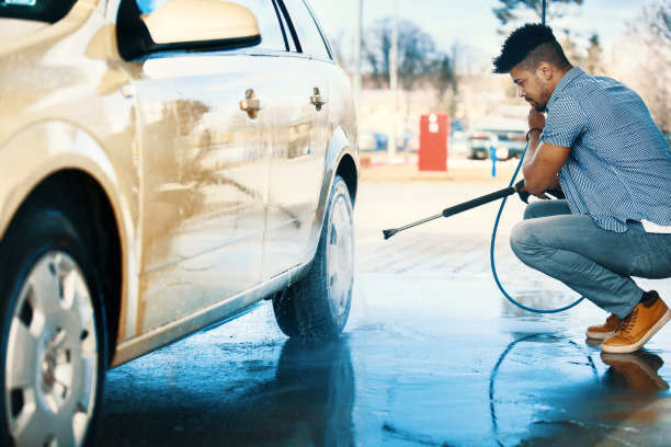 a man using high-pressure cleaning machine to car