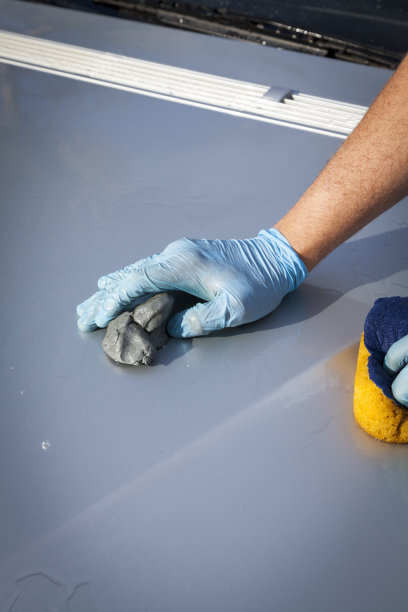 a people using a clay bar to remove dirts on the car