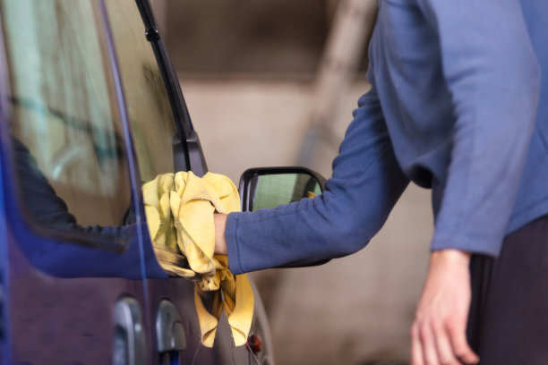 a people wiping the car with a yellow and soft fabric