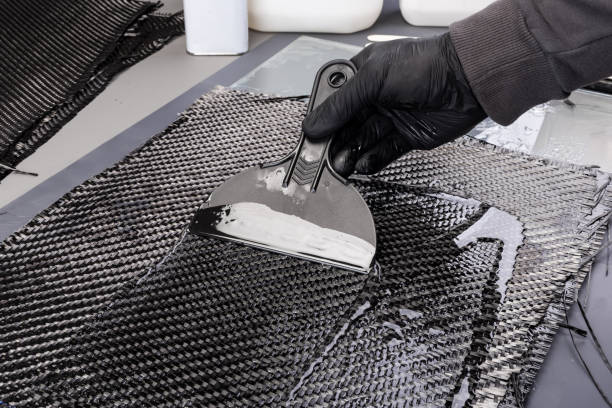 hand working epoxy resin into woven carbon fiber reinforcement cloth.